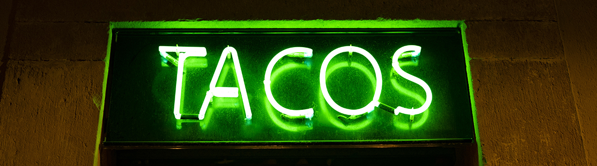 Green neon sign of the word TACOS