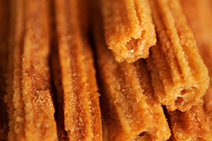 Stack of churro stick desserts covered in cinnamon and sugar.