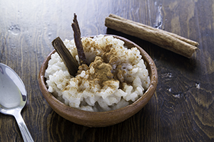 Small bowl of rice pudding with a cinnamon stick.