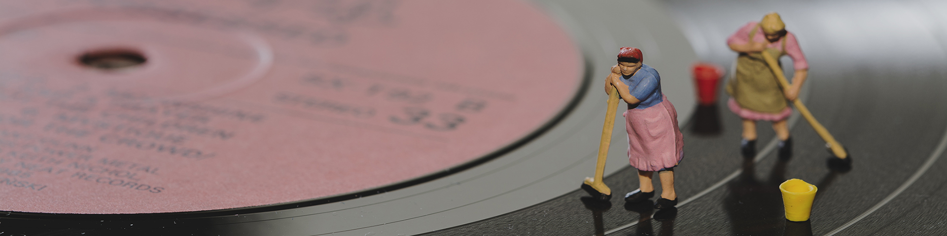 Two women cleaning the surafce of an LP record with mops